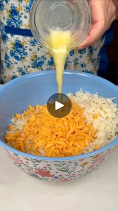 someone pouring cheese into a bowl with rice and other food in it on a table