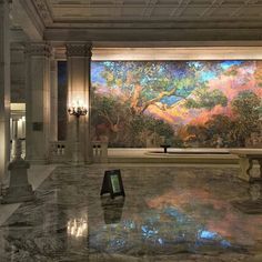 a large painting in the middle of a room with marble flooring and columns on either side