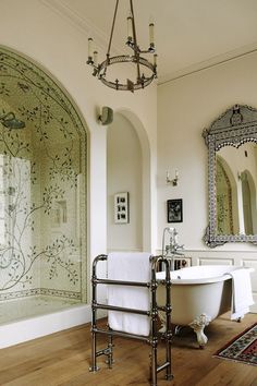 a bathroom with a bathtub, mirror and chandelier