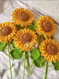 four yellow sunflowers with green leaves on a white cloth