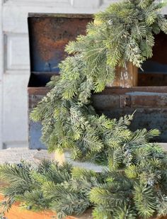 a close up of a wreath on top of an old trunk with pine needles hanging from it