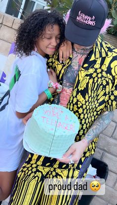 a man and woman hugging each other while holding a cake