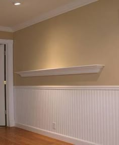 an empty room with hard wood floors and white waives on the wall, in front of a door