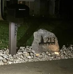 a mailbox sitting on the side of a road next to some rocks and grass