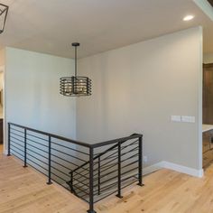 an empty room with hard wood floors and metal railings on the second floor,