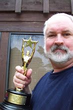 an older man holding up a trophy in front of a building with a wooden door