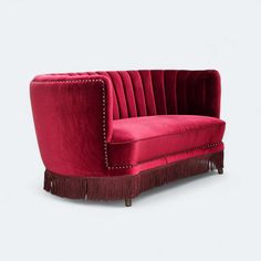 a red couch with tassels on the legs and back, sitting in front of a white background