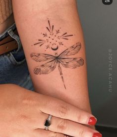 a woman's arm with a dragonfly tattoo on the left side of her arm