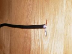 a close up of a piece of black wire on a wooden surface with a key attached to it