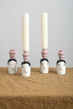 three candles are sitting on top of each other with faces painted on the candle holders