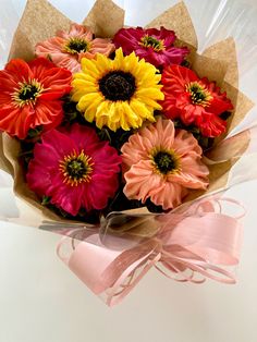 a bouquet of colorful flowers wrapped in brown paper