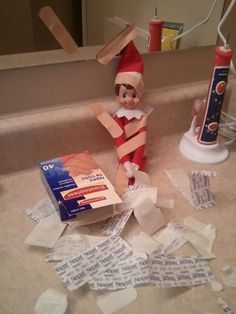 an elf is sitting on the floor next to some toilet paper and a tube of toothpaste