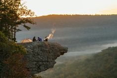 two people sitting on top of a cliff