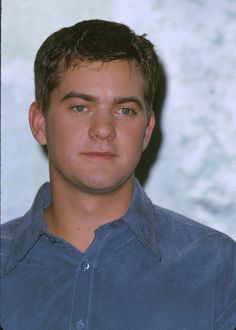 a young man in a blue shirt looking at the camera