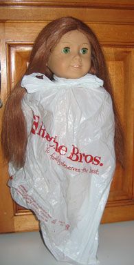 a doll is wrapped in plastic and standing on a countertop next to a wooden cabinet