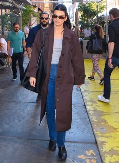 a woman walking down the street in a trench coat