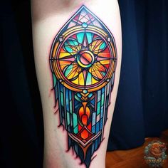 a colorful tattoo on the leg of a woman's thigh with an image of a dream catcher