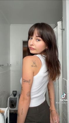 a woman with tattoos standing in a bathroom