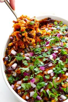 a bowl filled with mexican food and garnished with cilantro, red onion, and green onions