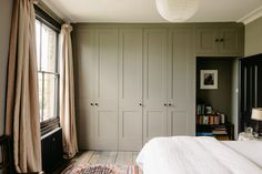 a bed sitting in a bedroom next to a window with curtains on the windowsill