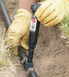 a person in yellow gloves is using a garden hose