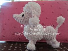 a white poodle sitting on top of a pink pillow