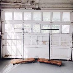 two wooden benches sitting in front of a garage door with three poles attached to it