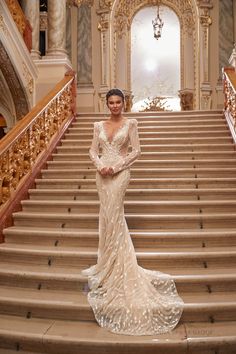 a woman in a wedding dress standing on the steps of an ornately decorated staircase