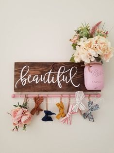 a wooden sign that says beautiful hanging on a wall next to flowers and other decorations