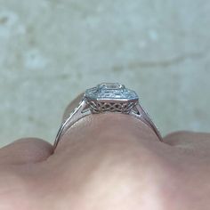 a close up of a person's hand holding a ring with a diamond on it