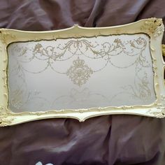 an ornate gold framed mirror sitting on top of a purple bed sheet covered in sheets