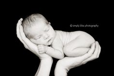 a black and white photo of a baby sleeping on its mother's hands in the dark