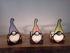 three different colored glass vases sitting on top of a wooden table