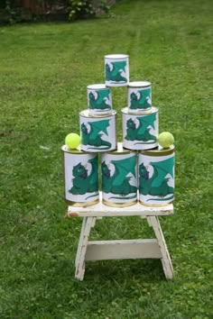 several cans stacked on top of each other in the grass with tennis balls inside them