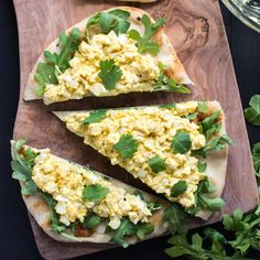 four flatbreads with eggs and greens on a cutting board