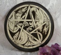 a black and white plate with an image of two snakes in the center, surrounded by purple crystals