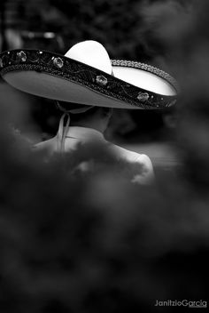 a black and white photo of a woman wearing a sombrero with jewels on it