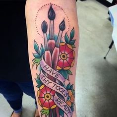 a woman's arm with tattoos on it and flowers in the center, which has a ribbon that says live without fear