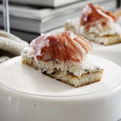 two pieces of bread with meat and cheese on them sitting on a table next to some books