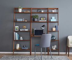 a room with a chair, desk and shelving unit on the wall in front of it