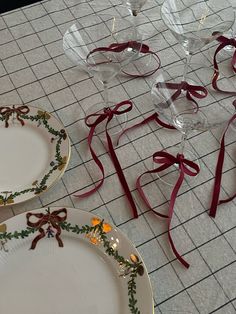 several empty wine glasses and plates on the floor with ribbons tied around them for decoration