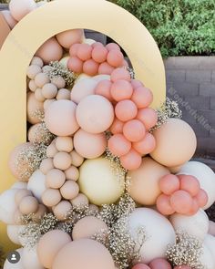 balloons are arranged in the shape of an o on top of each other, with white and peach colors