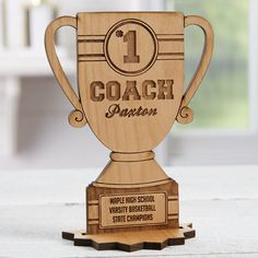 a wooden trophy with the words coach on it's front and side, sitting on top of a table