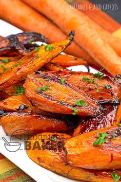 roasted carrots with balsami and parsley on a white plate next to sliced carrots