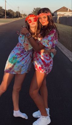 two young women are hugging on the side of the road wearing sunglasses and headbands