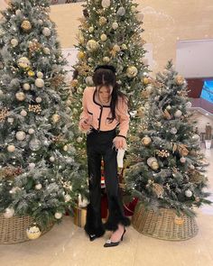 a woman standing in front of two christmas trees