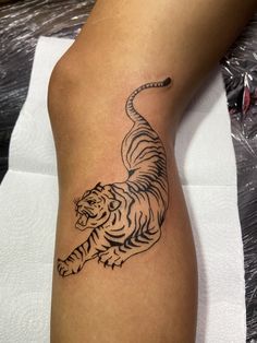 a black and white tiger tattoo on the left arm, with an arrow in it's tail