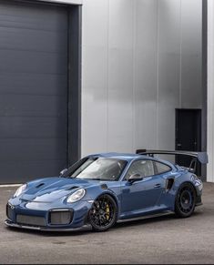 the blue porsche gtr is parked in front of a garage door and two large doors