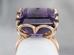 This ring is truly a statement! A large and beautiful deep purple amethyst sits in the center, with an amazing cut and a bold, sparkling color that flickers with bright pops of violet. The stone is expertly cut to really display the stone’s color and sparkle, this looping 18 karat gold mounting is all this stone needs to frame it to perfection! Metal: 18K Rose Gold Gem: Amethyst 16.19 Carats Gem Measurements: 17.2 x 14.1 mm, Emerald Cut Ring Size: 5 Marks: "308 AL 750" Stamped on the inside band Yellow Gold Amethyst Ring, Yellow Gold Sapphire Ring, Amethyst Cocktail Ring, Gold Drop Necklace, Emerald Cut Ring, Gold Amethyst Ring, Right Hand Ring, Emerald Cut Rings, Gold Jewelry Sets