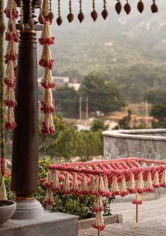 an outdoor area decorated with flowers and tassels on poles, along with a stone wall in the background